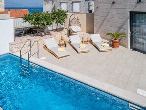 A swimming pool with lounge chairs and a stone wall. - Villa Stone Pearl - Two Bedroom Holiday House With Pool (Sutivan)