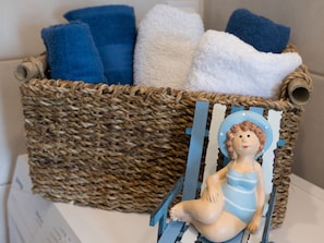 Un panier en osier contenant des serviettes et une petite figurine représentant une personne portant un maillot de bain bleu.