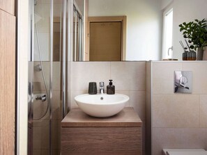 Une salle de bain moderne avec un grand lavabo rond, une douche en verre et un meuble-lavabo en bois.