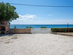 A gravel driveway leading to a stone wall with a white gate, a brick oven, and a view of the sea. - Home With Terrace Situated Near the Beach (Starigrad)