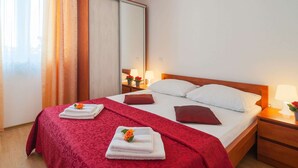 A hotel room with a bed, two bedside tables, a nightstand, a mirror, and a wardrobe. - Apartments Island Beat - Two Bedroom Apartment With Balcony (Supetar)