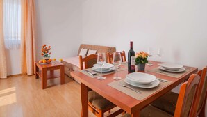 A dining area with a wooden table set for four, including plates, glasses, and cutlery. - Apartments Island Beat - Two Bedroom Apartment With Balcony (Supetar)