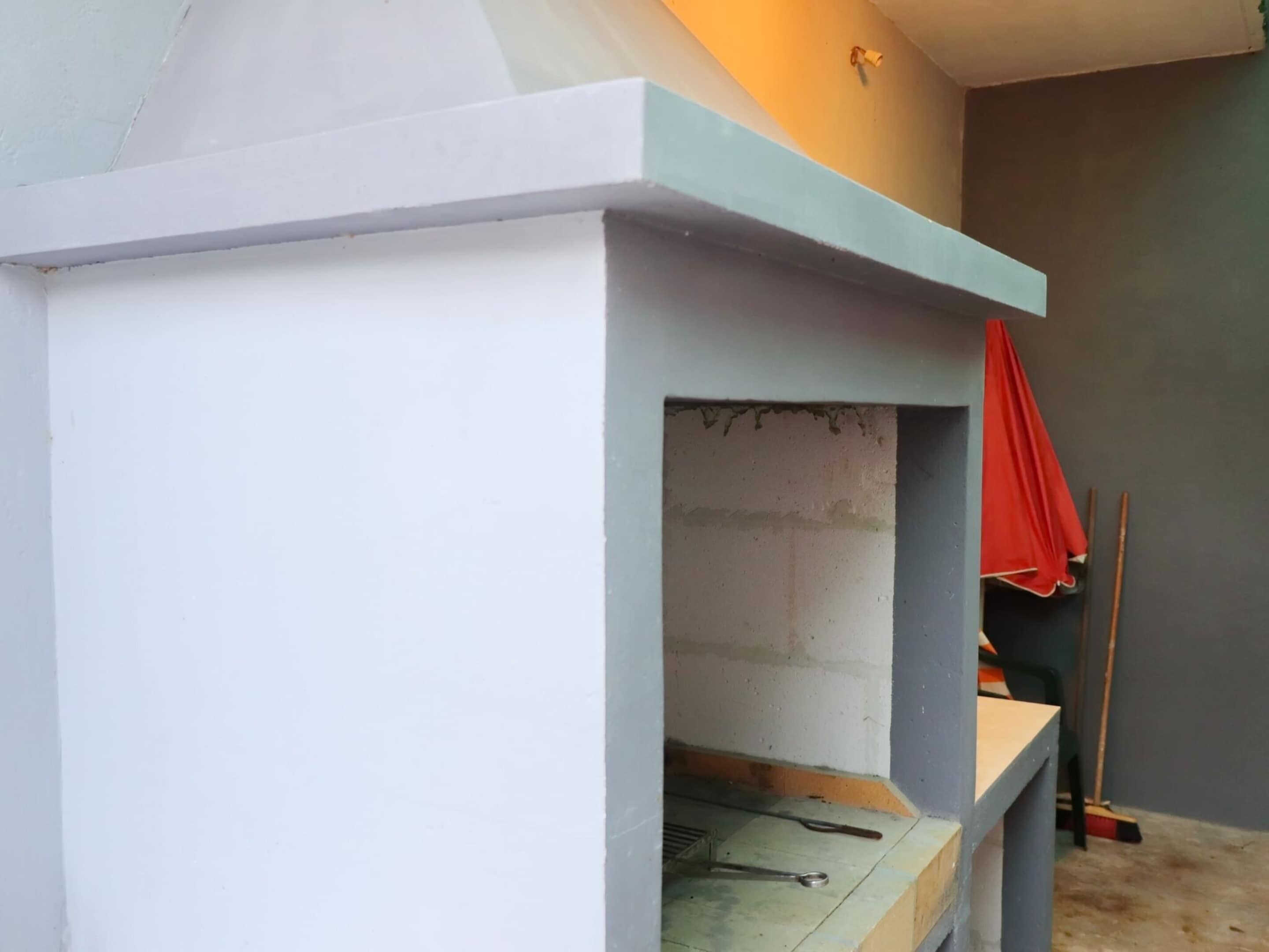 Een kamer met een blauw-witte wand, een rode doek die hangt, en een bezem die tegen de muur staat.