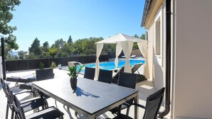 An outdoor patio with a table and chairs, a pool, and a covered area. - Villa in Starigrad With Heated Pool (Starigrad)