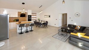 A modern kitchen with white cabinets, a dining area with a table and chairs, a sofa, and a coffee table. - Villa in Starigrad With Heated Pool (Starigrad)