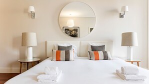 Ein Hotelzimmer mit einem großen Bett, zwei Nachttischen, zwei Wandlampen, einem runden Spiegel über dem Bett und einem gerahmten Bild an der Wand.