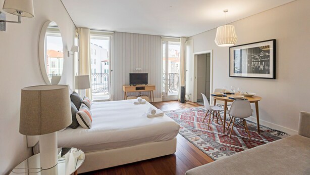 Ein Hotelzimmer mit einem großen Bett, einem Schreibtisch, einem Fernseher und einer Essecke.