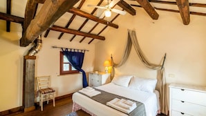 A cozy bedroom with a wooden ceiling, a bed with white linens, a bench, a chair, and a nightstand with a lamp. - Belvilla by OYO Villa Osimo (Osimo)