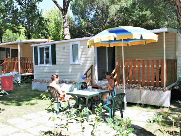 A mobile home with a porch, a table, and chairs. There is a wooden fence and a small garden with flowers. - Mobile Home by Lake Trasimeno Fun (Castiglione del Lago)