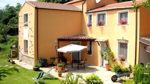 A two-story house with a patio area, outdoor seating, and potted plants. - Apartment in Liguria Near Toirano Caves (Vezzi Portio)