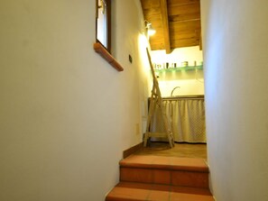 A narrow staircase with a wooden handrail and a light fixture above.
