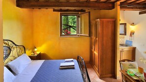 A bedroom with a bed, a wooden wardrobe, a window with a view of greenery, and a small table with a bowl and a mug. - Holiday Home in Pontano With Garden (Sant'Angelo in Pontano)