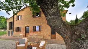 A rustic stone building with a brick facade, wooden shutters, and a gravel patio with wicker furniture. - Holiday Home in Pontano With Garden (Sant'Angelo in Pontano)