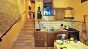 A kitchen with a wooden staircase, a sink, a stove, and a dining table set with plates and utensils. - Holiday Home in Pontano With Garden (Sant'Angelo in Pontano)