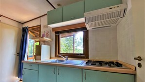 A kitchen with teal cabinets, a window, a sink, and a stove. - Belvilla by OYO Lovely Bungalow With a Shared Pool (Capraia e Limite)