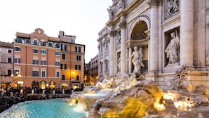 Una fontana storica con statue, circondata da architettura classica e una folla di persone.