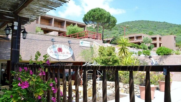 A restaurant with outdoor seating, a stone facade, and a view of a hill. - Apartment Near Golfo di Cugnana (Olbia)