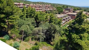 A residential area with multiple buildings, surrounded by dense greenery and hills in the background. - Apartment Near Golfo di Cugnana (Olbia)