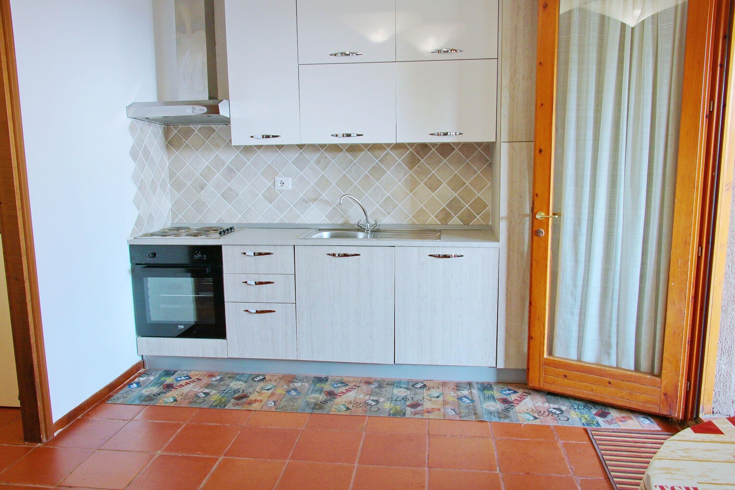 A kitchen with white cabinets, a black oven, and a tiled backsplash.