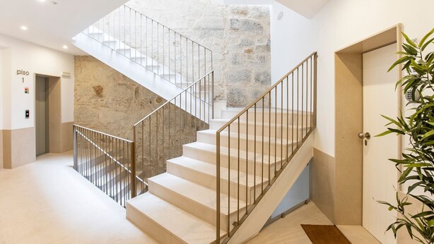 Eine moderne Treppe mit Metallgeländern, einer Steinsäule und einer Tür mit Zahlenschloss.