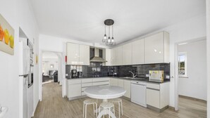 Una cocina moderna con armarios blancos, encimera de granito y una mesa de comedor redonda con taburetes.