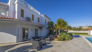 Un edificio blanco con marcos de ventana amarillos y un patio con azulejos y mobiliario exterior.
