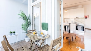 Un apartamento moderno con comedor, cocina y balcón con plantas.