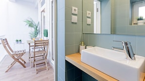Un baño moderno con un lavamanos grande, un espejo y una silla de madera.