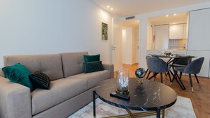 A living room with a sofa, a coffee table, and a dining area with chairs and a table.