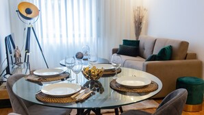 Uma área de refeições com uma mesa de vidro, pratos e copos de vinho.