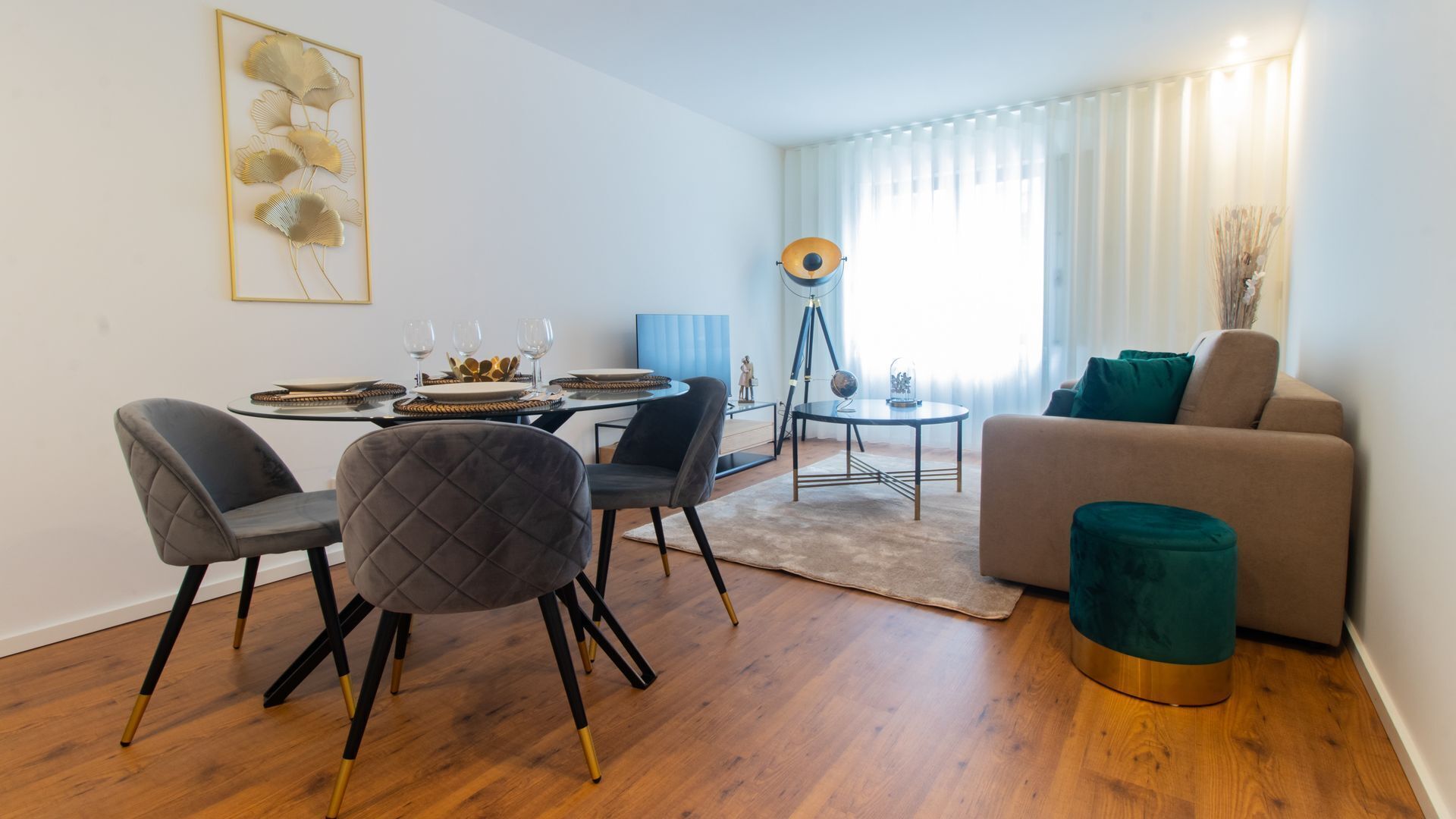 Uma sala de estar moderna com área de jantar, apresentando um sofá, cadeiras, mesa de centro e mesa de jantar posta para quatro pessoas.