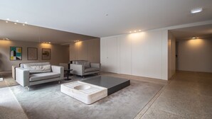 Uma sala de estar moderna com dois sofás cinzas, uma mesa de centro e um armário branco grande.