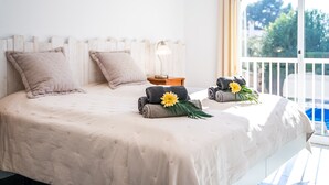 Un lit bien fait, avec deux oreillers, une lampe de chevet et des serviettes ornées de motifs floraux sur un balcon.