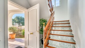 Un escalier avec des rampes en bois et des marches en marbre, menant à une porte dotée d’une poignée de porte en laiton.