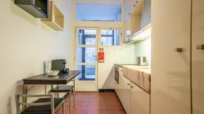 Une cuisine compacte équipée d’une machine à café, d’une petite table et d’une chaise.