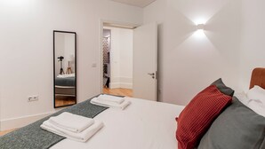 Una moderna camera d'albergo con un letto grande, uno specchio e un'anta che conduce al bagno.