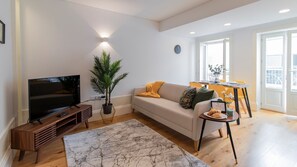A modern living room with a TV, sofa, coffee table, and a dining area with a table and chairs. - Rodrigues de Freitas 391 F by LovelyStay (Porto)
