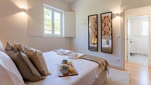 Ein Schlafzimmer mit einem Bett, Kissen, einer Ablage mit Tassen und Saft sowie zwei an der Wand befestigten Spiegeln.