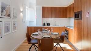 Eine moderne Küche mit Holzschränken, einer Edelstahl-Mikrowelle und einem Essbereich mit rundem Tisch und Stühlen.