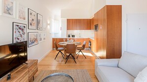 Ein modernes Wohnzimmer mit Flachbildfernseher, einer Couch und einem Essbereich mit Holztisch und Stühlen.