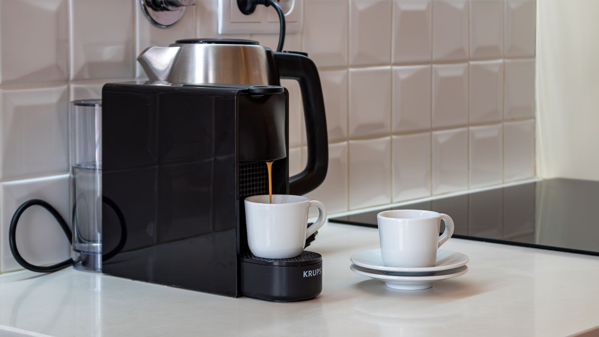 Una máquina de café con dos tazas sobre una encimera.