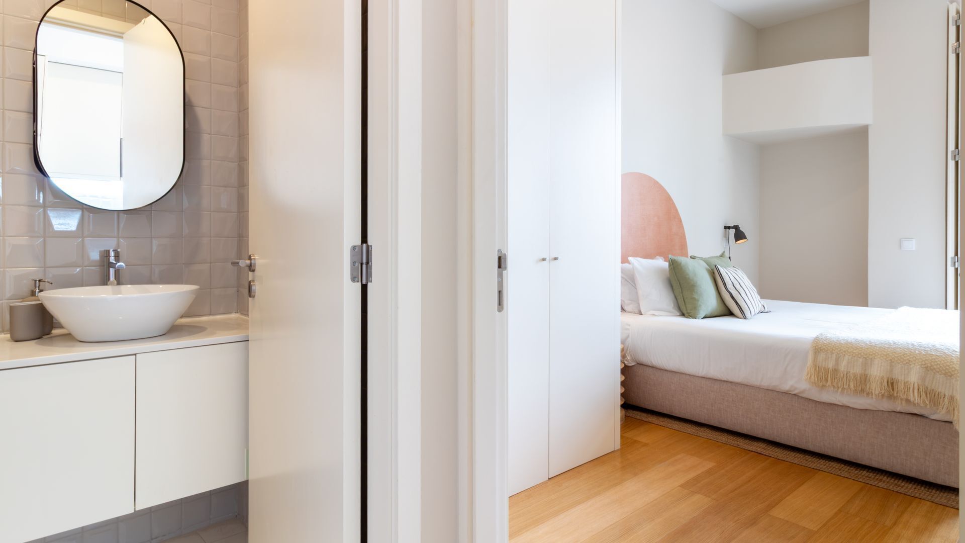 Ein modernes Badezimmer mit Waschbecken und Spiegel, ein Schlafzimmer mit Bett und Nachttisch sowie ein Holzboden.