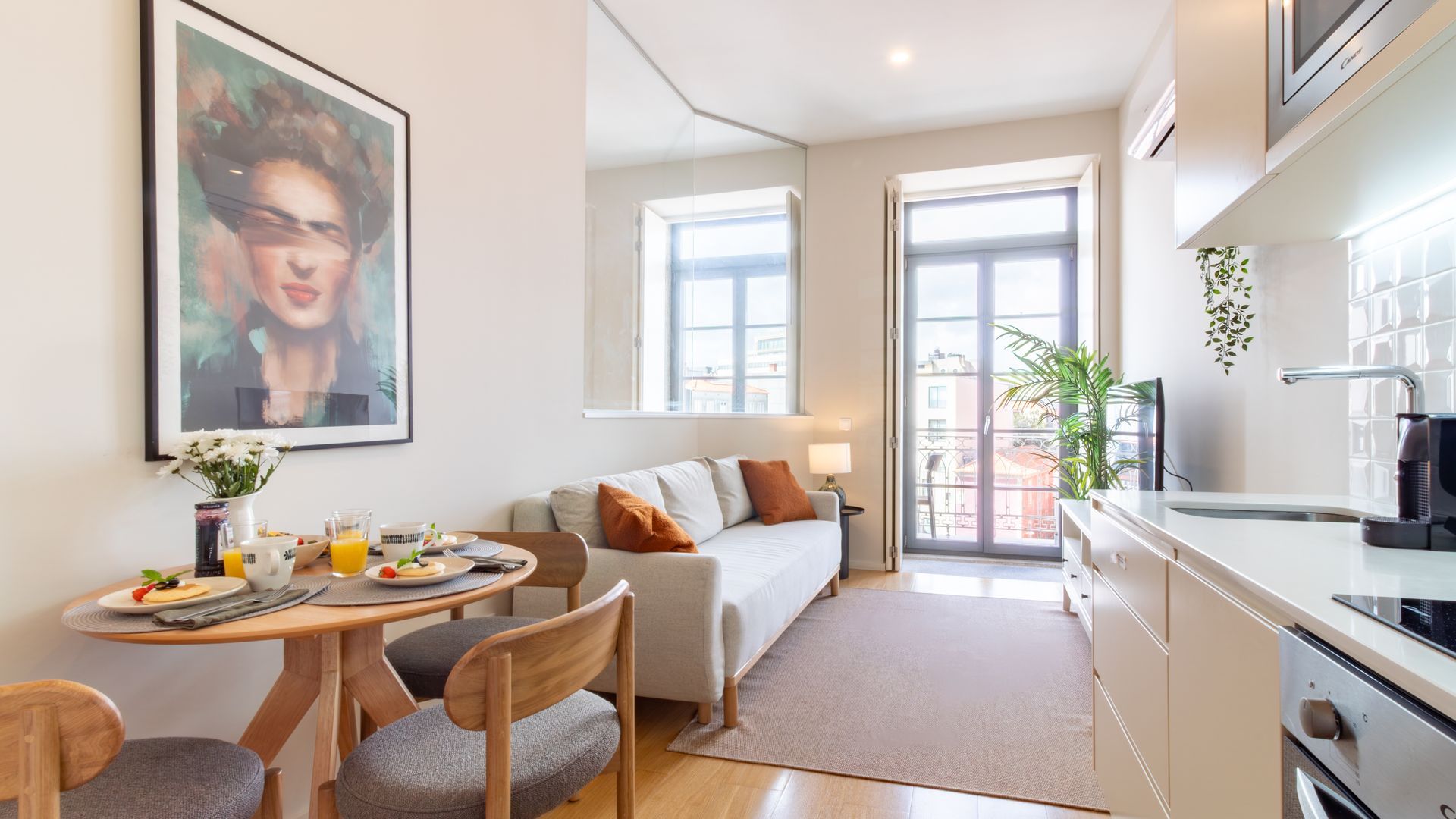 A modern apartment with a dining area, kitchenette, and a balcony with a view.