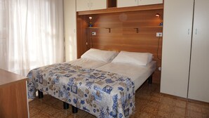 A bedroom with a bed, a desk, and a wardrobe. - Holiday Home in Caorle Near Spiaggia Tartaruga (Caorle)