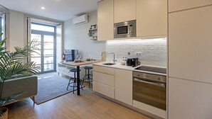 Una cocina moderna con armarios blancos, un microondas de acero inoxidable, un horno empotrado y un amplio ventanal que proporciona luz natural.