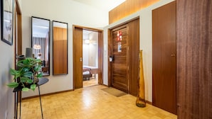 A hallway with wooden flooring, a plant, framed mirrors, and a door with a red sign. - Firmeza388 1E - Charming Apartment by LovelyStay (Porto)