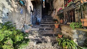 A narrow stone staircase in a historic building with potted plants and flowers on the sides. - Apartment at Lago di Como Near Dervio Beach (Dervio)