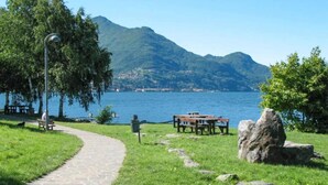 A park with a paved path, picnic tables, benches, and a large rock. - Apartment at Lago di Como Near Dervio Beach (Dervio)