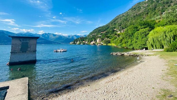 A lake with boats, a small building, and a hillside with houses. - Apartment at Lago di Como Near Dervio Beach (Dervio)
