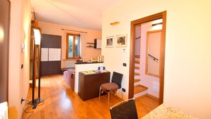 A compact living space with a kitchenette, a dining area, and a staircase. - Belvilla by OYO Casa Cristina Meina Centro 4 (Meina)